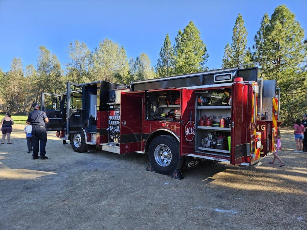 Fire truck at El Dorado Adventist School outdoor safety event, kids learning fire safety and rescue techniques.