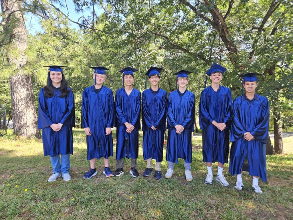 Graduating students in blue caps and gowns at El Dorado Adventist School outdoor ceremony.