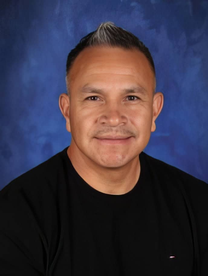 Portrait of a man in front of a blue background at El Dorado Adventist School.