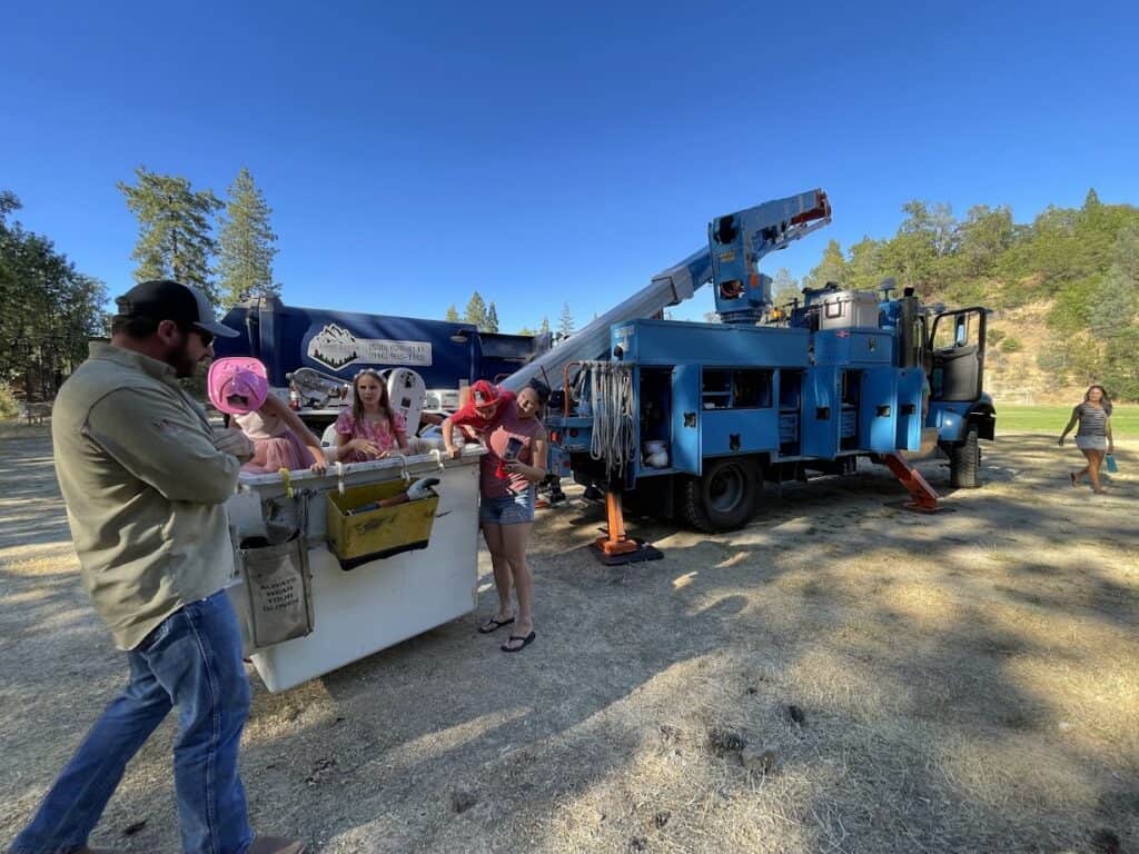 School children exploring a tree service truck during an outdoor educational activity at El Dorado Adventist School.