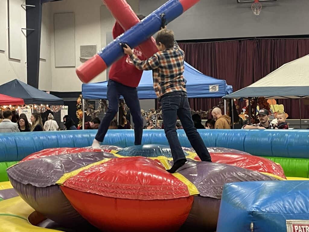 Children playing on a colorful inflatable bouncy castle at El Dorado Adventist School event.