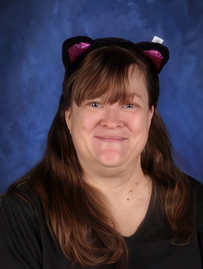 El Dorado Adventist School teacher portrait, friendly educator with cat ear headband, blue background.