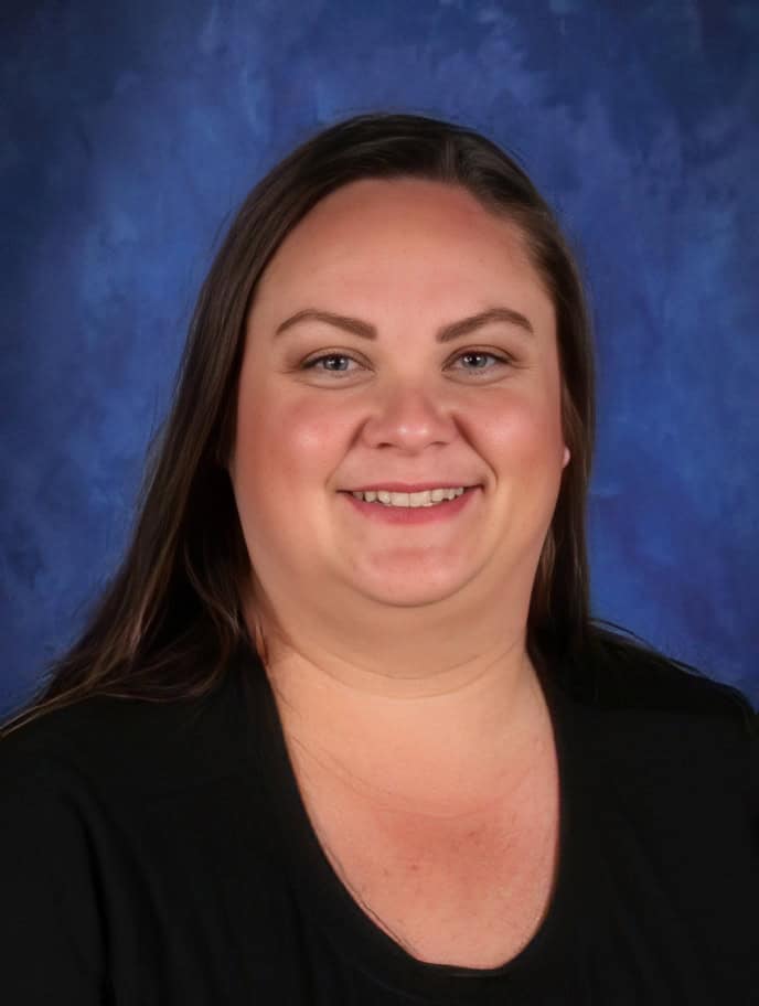 Teacher portrait at El Dorado Adventist School, smiling educator in front of blue background.