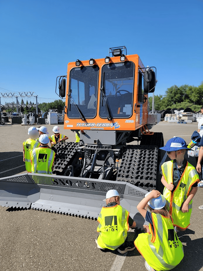 Tucker Terra tracked vehicle with children visiting, outdoor educational activity at El Dorado Adventist School, learning about construction equipment.