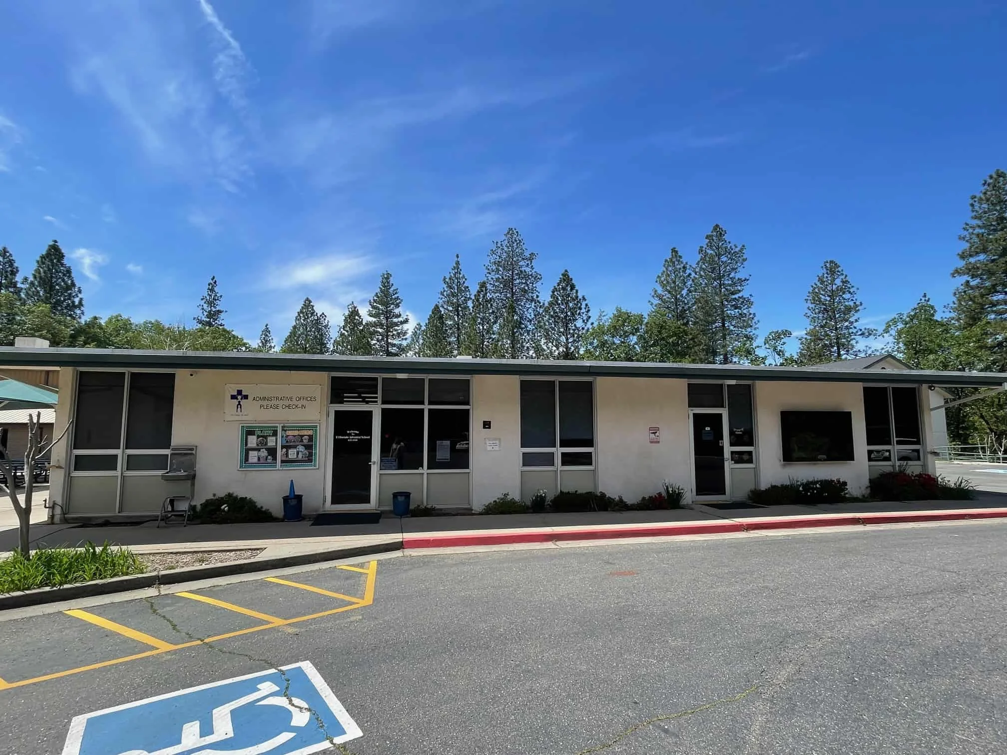 Accessible school office building at El Dorado Adventist School, surrounded by pine trees in a serene environment.