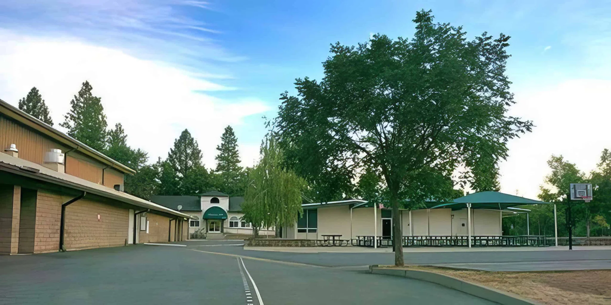 Colorful school campus with large trees, sports area, and modern buildings at El Dorado Adventist School.